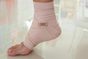 Man with ankle sprain elastic bandage for ankle injury and feeling pain photo
