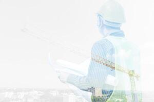 Double exposure image of professional engineer in protective helmet and blueprints paper at building construction site photo