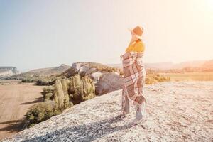 Woman in a Hat and Blanket Standing on a Mountaintop photo