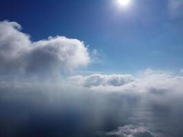 Aerial view. The drone flies over foggy and fluffy clouds. Blue sky sun and sea fog. Abstract aerial nature summer ocean sunset sea and sky background. Vacation, travel and holiday concept photo