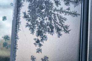 Selective focus. First frost on a frozen black plastic, late autumn close-up. Beautiful abstract frozen microcosmos pattern. Freezing weather frost action in nature. Winter backdrop. photo