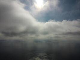 Aerial view. The drone flies over foggy and fluffy clouds. Blue sky sun and sea fog. Abstract aerial nature summer ocean sunset sea and sky background. Vacation, travel and holiday concept photo