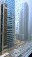 Rain falling on window in skyscraper apartment. Dark and stormy rainy day in big city life. View of dreary Hong Kong cityscape whilst rain drops fall on the window. Abstract somber moody background. video