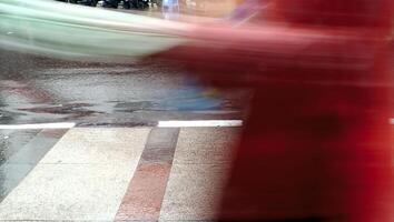 Blurred motion of unknown person pedestrians walking on wet city pavement during a rainy days photo