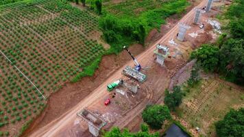 Aerial view of a new road development or highway under construction. Top view from a drone over road construction workers amidst mountains. Construction Site with Cranes and Heavy Equipment. video