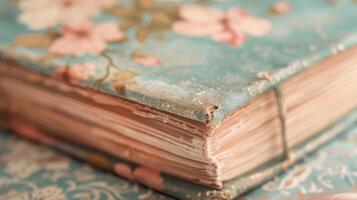 The cover of the book is made of a soft velvety material with a floral design and faded pastel colors. The title is written in cursive font adding to its vintage charm photo