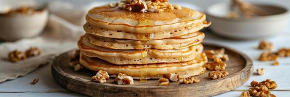 A stack of fluffy vegan pancakes topped with melted coconut oil and a handful of crushed walnuts photo