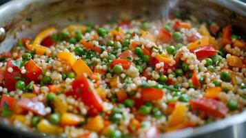 A colorful array of vegetables including diced bell peppers and peas mixed into a pot of simmering buckwheat pilaf photo