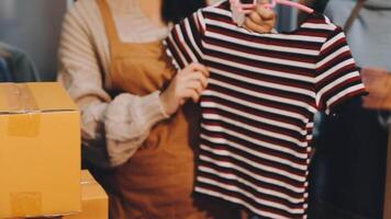 Fashion blogger concept, Young Asian women selling clothes on streaming.Startup small business SME, using smartphone or tablet taking receive and checking in home office video