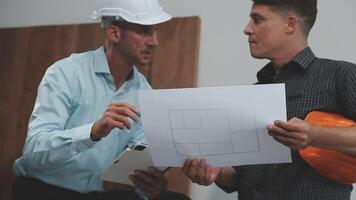 Teamwork men in construction site, Two civil engineer or professional foreman in safety helmet hard hat using blueprint in digital tablet working while standing at industrial factory, teamwork concept video