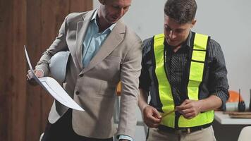 Teamwork men in construction site, Two civil engineer or professional foreman in safety helmet hard hat using blueprint in digital tablet working while standing at industrial factory, teamwork concept video