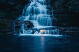 Waterfall in Dark with Light Shining on It Background photo
