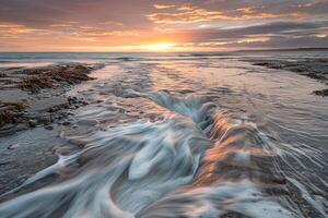 Sunset Over Ocean Waves Crashing on Shore at Dusk photo