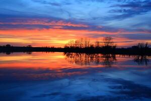 Sunset over lake with clouds reflected in water background photo