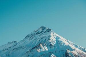 a mountain peak with a blue sky in the background and a nature background photo