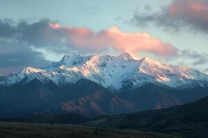 a mountain range with a large snow covered peak background photo