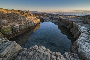 A Pool of Water Surrounded by Rocks with a Scenic Background photo