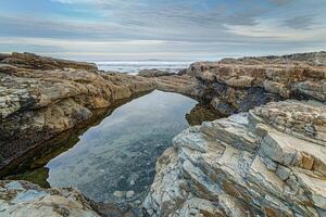 A Small Body of Water Surrounded by Rocks with a Scenic Background photo