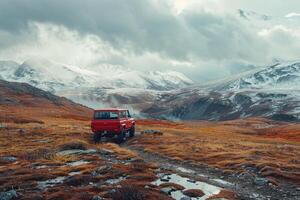 red car on a mountain road with snowcovered mountains in the background photo