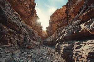 a narrow canyon with rocks and sun shining through background photo