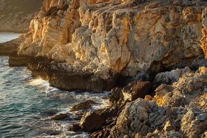 a rocky cliff overlooking the ocean with waves crashing into it and background photo