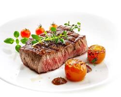 a piece of steak with tomatoes and herbs on a white plate background photo
