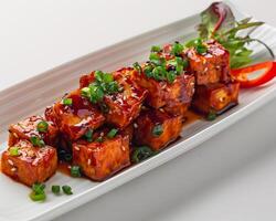 a plate of tofu with sauce and green onions background photo
