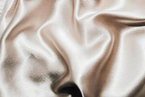 Golden shiny texture of silk satin satin with folds. photo