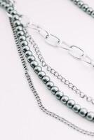 A necklace of gray beads with chain decorations on a white aesthetic background. photo