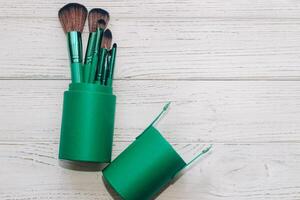 Green case with make-up bones on a wooden table. photo