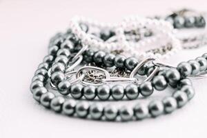 A necklace of gray beads with chain decorations on a white aesthetic background. photo