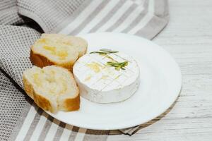 White baguette cut into pieces with olive oil and Camembert cheese on the table photo