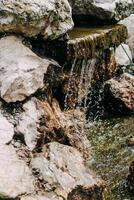 Artificial waterfall of stones and flowers in a landscaped green garden photo