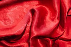 Red shiny texture of silk satin satin with folds. photo