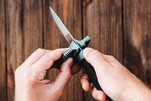 hands sharpening a knife on a wooden background photo