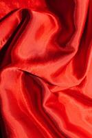 Red shiny texture of silk satin satin with folds. photo