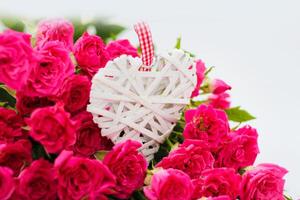 Decorative white heart made of vines, Valentine's Day on the background of a bouquet of roses photo