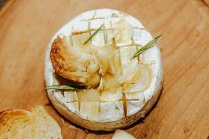 White baguette with olive oil and baked Camembert cheese on the table. photo