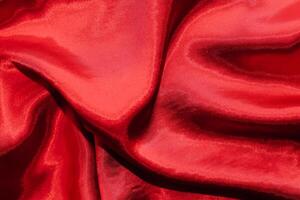 Red shiny texture of silk satin satin with folds. photo