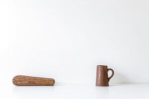 Minimalist Still Life with Wooden Object and Clay Mug on White Background photo