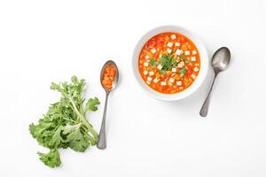 Bowl of vegetable soup with a spoon and celery on white background photo