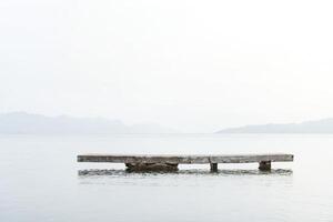 Minimalist Concrete Dock on Calm Water with Mountains in the Background photo