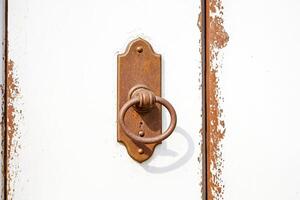 Old door handle on a white door with peeling paint photo