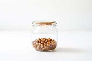 Closeup of a glass jar filled with almonds on a white background photo