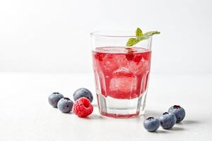 Raspberry and blueberry infused cocktail with ice in a glass photo