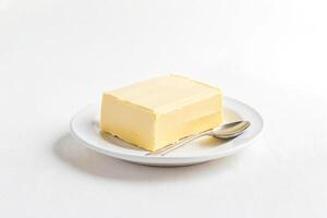 A single stick of butter on a white plate with a spoon photo