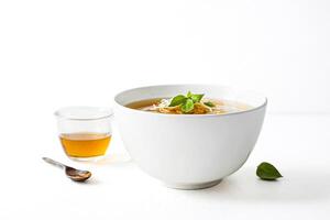 White bowl of soup with basil garnish and a side of honey photo