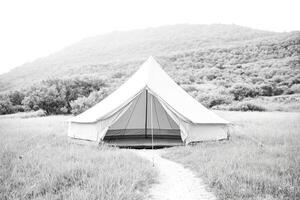 Tent in a Field with Trees in the Background photo