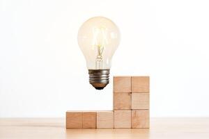 Lightbulb Hovering Above Wooden Blocks on White Background photo