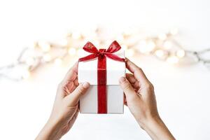 Close-up of hands holding a gift box with red ribbon photo
